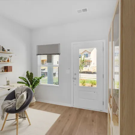 Bright modern home office with wooden desk, round chair, floating shelves, potted plants, and natural light.