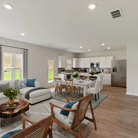 Open-concept living and kitchen area with modern white cabinets, wooden flooring, and cozy seating with blue accents.
