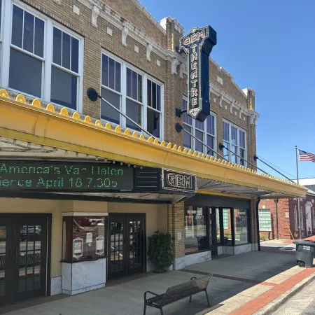 Historic theater exterior with marquee and yellow awning on a sunny day, showcasing brick architecture.