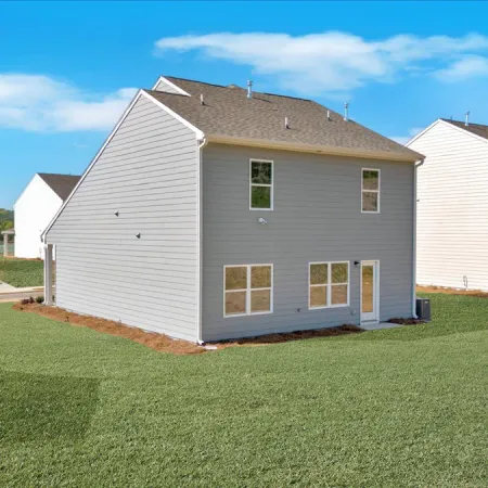 Suburban neighborhood with modern two-story houses and green lawns under a blue sky with clouds.