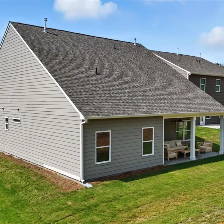 Modern gray single-story house with covered patio and neatly trimmed green lawn in a suburban neighborhood.