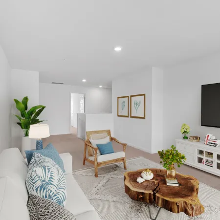 Bright modern living room with white sofa, wooden chair, tree stump coffee table, and large flat-screen TV
