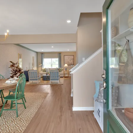Stylish open-concept dining area featuring green chairs, elegant chandelier, and tasteful decor in a bright home.