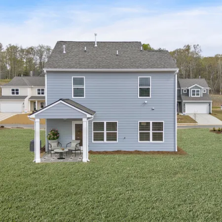 Modern two-story house with a porch in a suburban neighborhood surrounded by green grass.