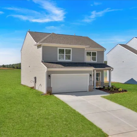 Modern two-story house with a spacious front yard and blue sky backdrop.