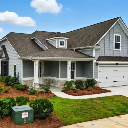 Modern gray single-story house with white trim, attached garage, landscaped lawn, and clear blue sky.