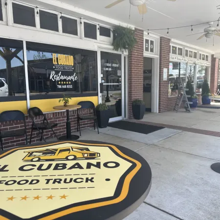 Outdoor seating area at El Cubano food truck restaurant with branded tables and chairs in a brick storefront.