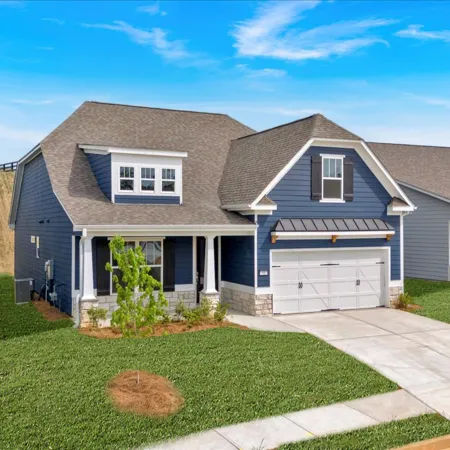 Modern blue and gray suburban homes with manicured lawns under a clear blue sky on a sunny day