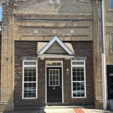 Front view of a brick building with large windows and a decorative entrance.