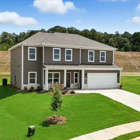 Modern two-story brown house with well-maintained lawn and double garage under blue sky with clouds