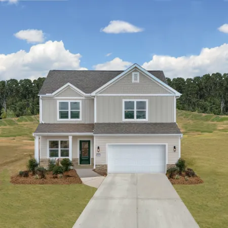 Modern two-story home with garage and landscaped yard against blue sky and greenery.