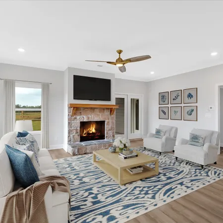 Bright living room with stone fireplace, wall-mounted TV, white sofa, blue patterned rug, and modern decor.