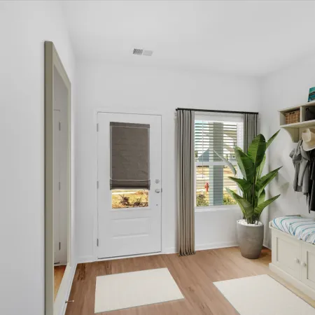 Bright and inviting entryway with a coat rack, storage bench, and potted plant in a modern home.