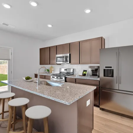 Modern kitchen with granite island, wooden cabinets, stainless steel appliances, and natural light.