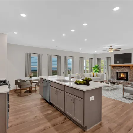 Modern kitchen and living room with bright lighting, fireplace, and elegant furnishings, creating a cozy atmosphere.