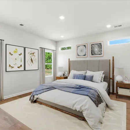 Bright modern bedroom with large bed, neutral decor, wooden floors, and botanical artwork on walls overlooking garden.