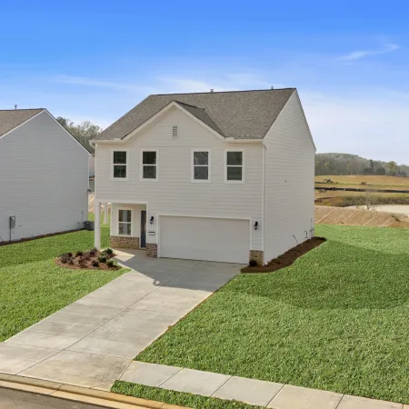 Modern two-story white house with garage and well-kept green lawn in a suburban neighborhood on a clear day