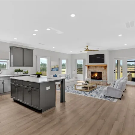 Open concept kitchen and living room with gray cabinets, kitchen island, fireplace, and hardwood floors under natural light