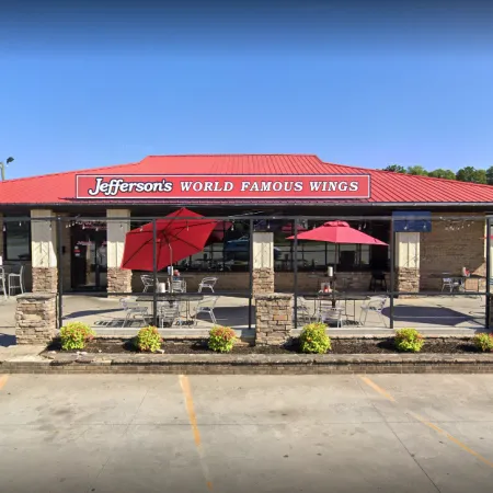 Jefferson's World Famous Wings restaurant with outdoor seating and red umbrellas under a clear blue sky.