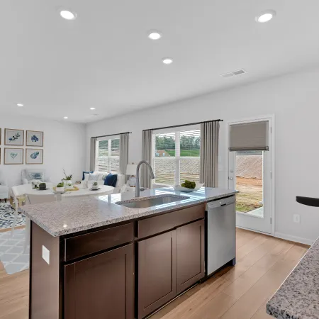 Modern kitchen interior with sleek design, featuring an island, granite countertops, and natural light.