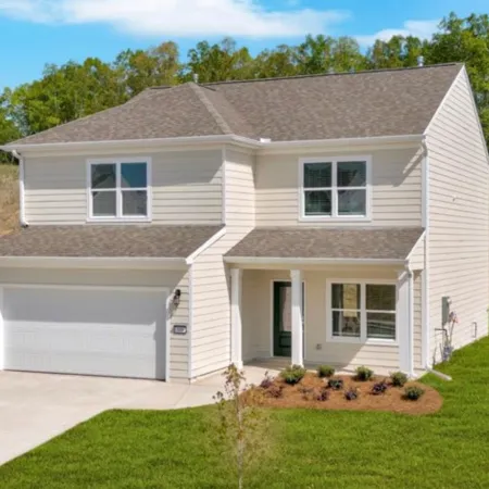 Modern two-story house with white siding, attached garage, front porch, and neatly landscaped lawn in suburban area