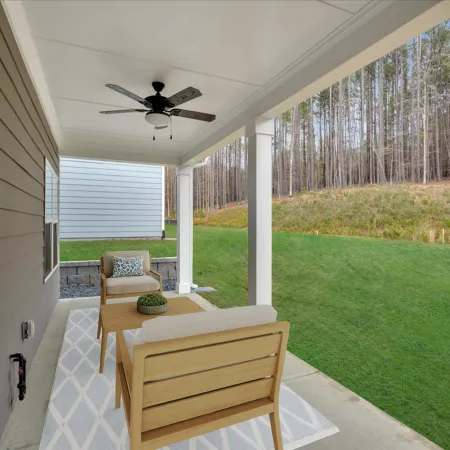 Outdoor patio area with seating, ceiling fan, and lush green landscape in the background.