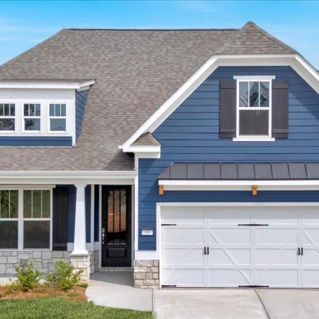 Modern blue two-story house with white trim, large garage, and small front porch under clear sky.