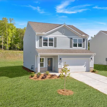 Modern suburban home with green lawn and trees under a clear blue sky.