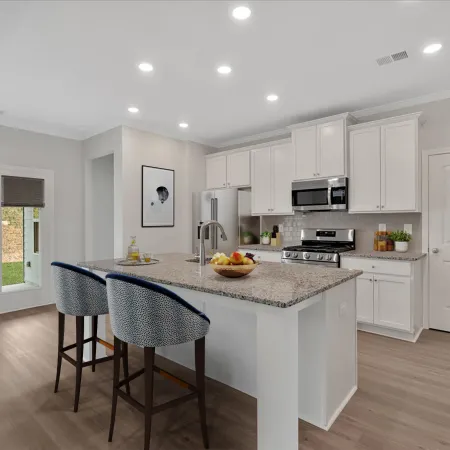 Modern kitchen with granite island, two patterned bar stools, white cabinets, stainless steel appliances, and light wood flooring