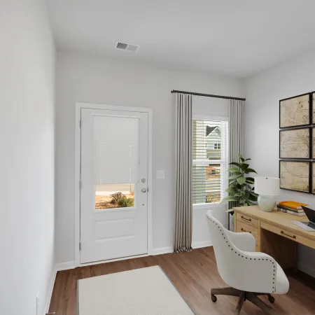 Bright home office with wooden desk, white chair, decorative world map, and a window with gray curtains.