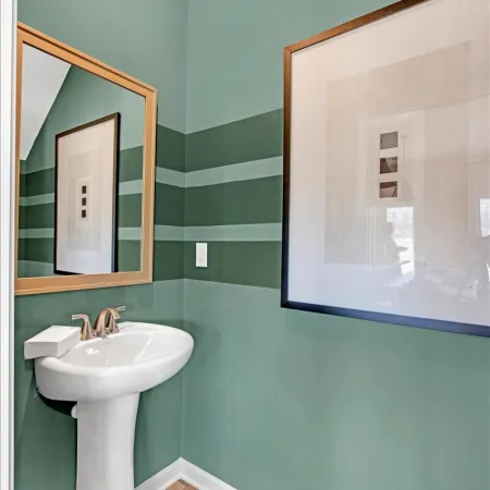 Elegant green bathroom with modern sink, framed artwork, and stylish striped walls.