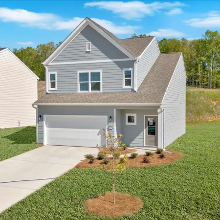 Modern two-story gray house with attached garage, landscaped front yard, and clear blue sky background.