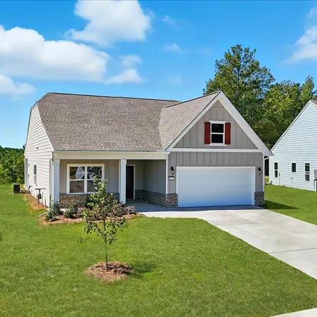 Single-story modern house with gray siding, two-car garage, front porch, and well-kept green lawn under blue sky.