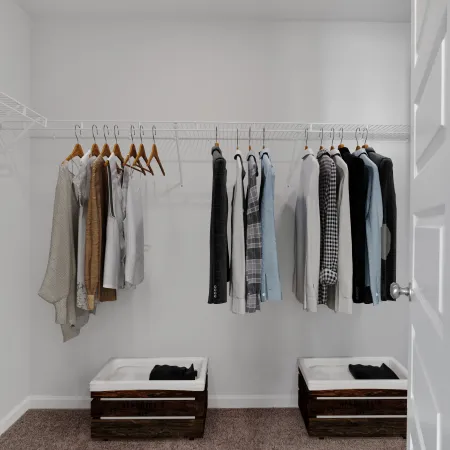 Minimalist closet with hanging neutral-toned clothes and two wooden storage bins on carpeted floor.