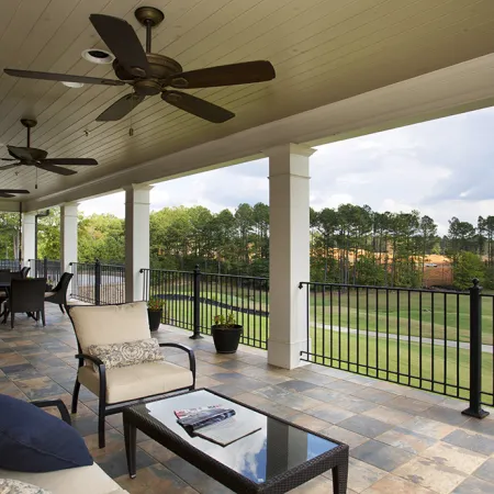 Spacious covered patio with ceiling fans overlooking a golf course, featuring lounge and dining furniture.