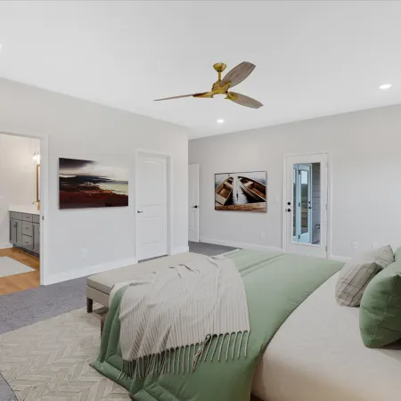 Modern bedroom with green bedding, gray carpet, ceiling fan, and doorway leading to bathroom and outside patio.