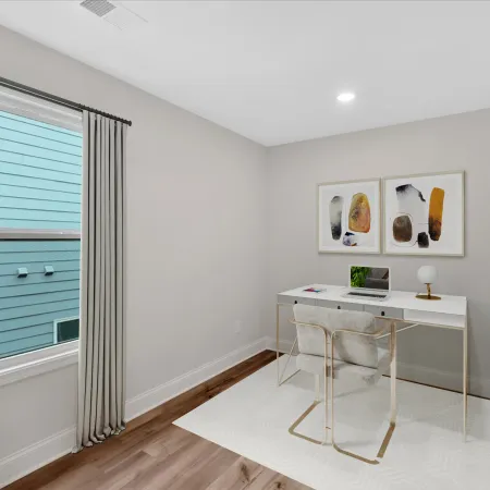 Modern home office featuring a sleek desk, decor, and large window with greenery for a bright atmosphere.