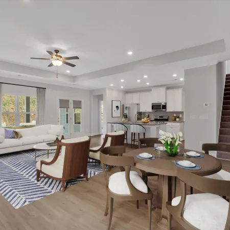 Spacious open-plan living and dining area with modern kitchen, wooden floors, white walls, and staircase leading upstairs