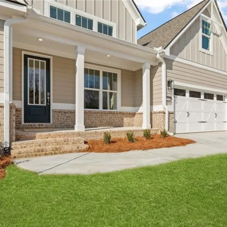 Modern suburban house exterior with gray siding, brick accents, black front door, and a two-car garage