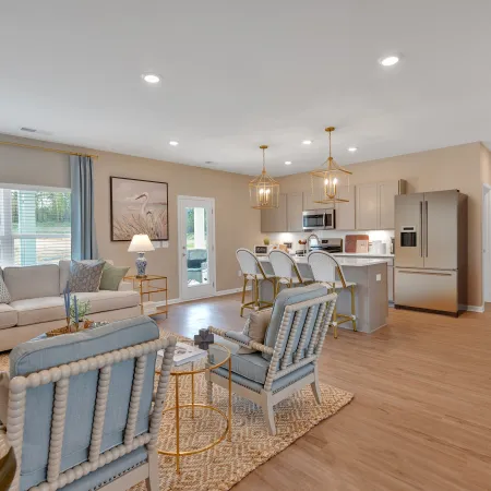 Modern living room and kitchen with stylish decor and natural light, featuring soft colors and elegant furnishings.
