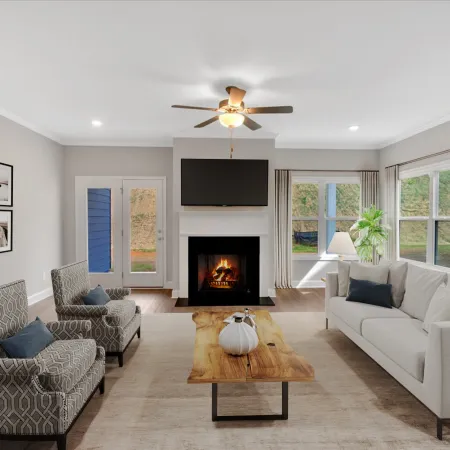 Bright modern living room with patterned chairs, white sofa, wooden coffee table, fireplace, and ceiling fan.