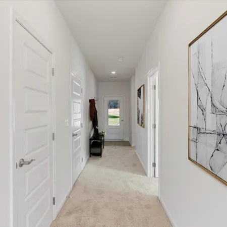 Bright hallway with white paneled doors, beige carpet, modern art, and a bench near a glass door at the end.