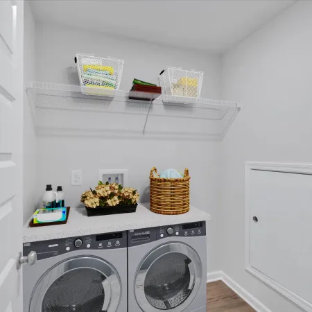 Modern laundry room with front-loading washer and dryer, wire shelf, laundry basket, and cleaning supplies.