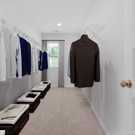 Spacious, organized walk-in closet with hanging clothes and storage bins on a soft carpet.
