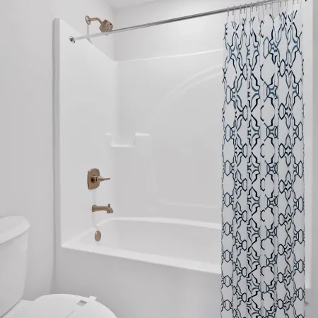 Modern bathroom features white tub, patterned shower curtain, and light wood flooring.
