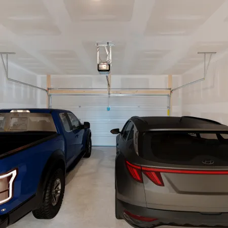 Two cars parked in a spacious, clean garage with unfinished walls and ceiling.