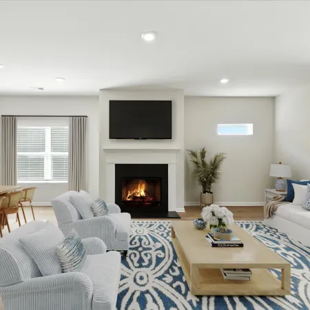 Bright modern living room with fireplace, white sofa, striped armchairs, blue patterned rug, and wooden dining table.