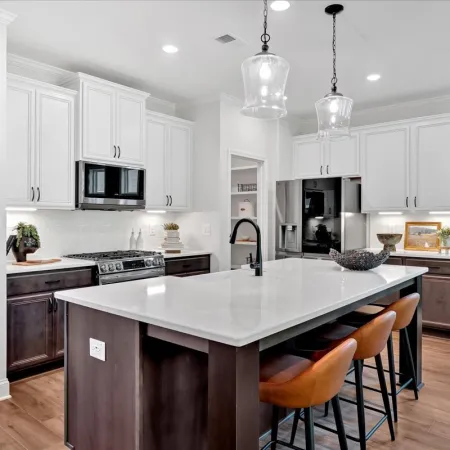 Modern kitchen with white upper cabinets, dark lower cabinets, large island, and green accent wall
