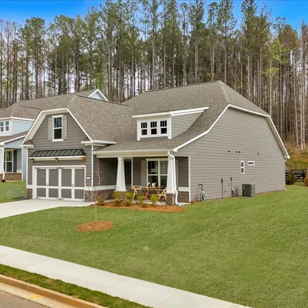 Modern suburban homes with green lawns nestled against a backdrop of trees.