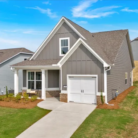 Modern gray house with a front porch, single garage, and landscaped yard under a blue sky.